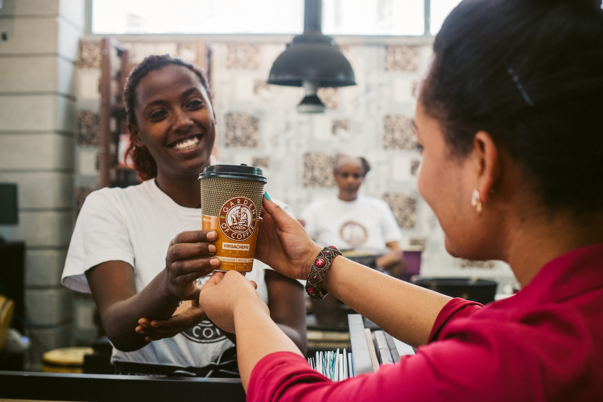 A Garden of Coffee team member hands a customer a bag of Sidamo beans