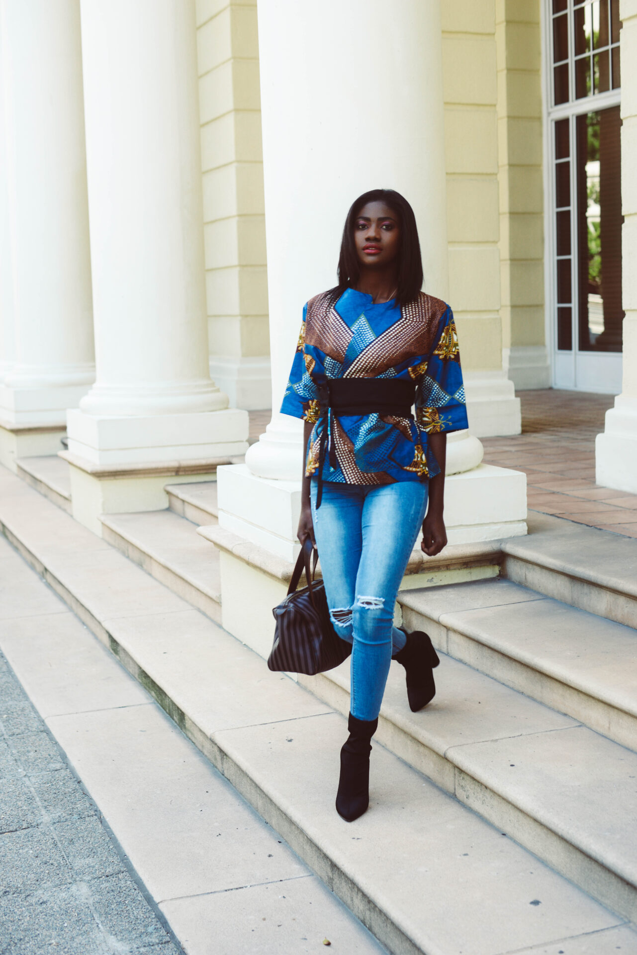 Model walking between columns in ankara top and jeans
